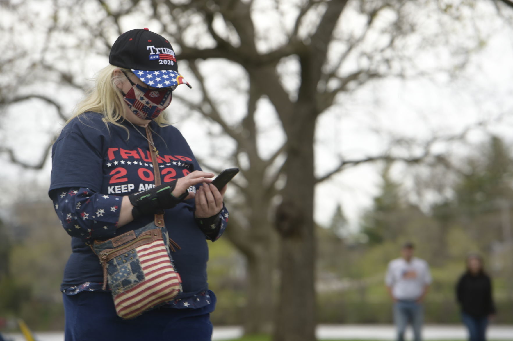 Woman at protest wearing Donald Trump-branded apparel and a mask